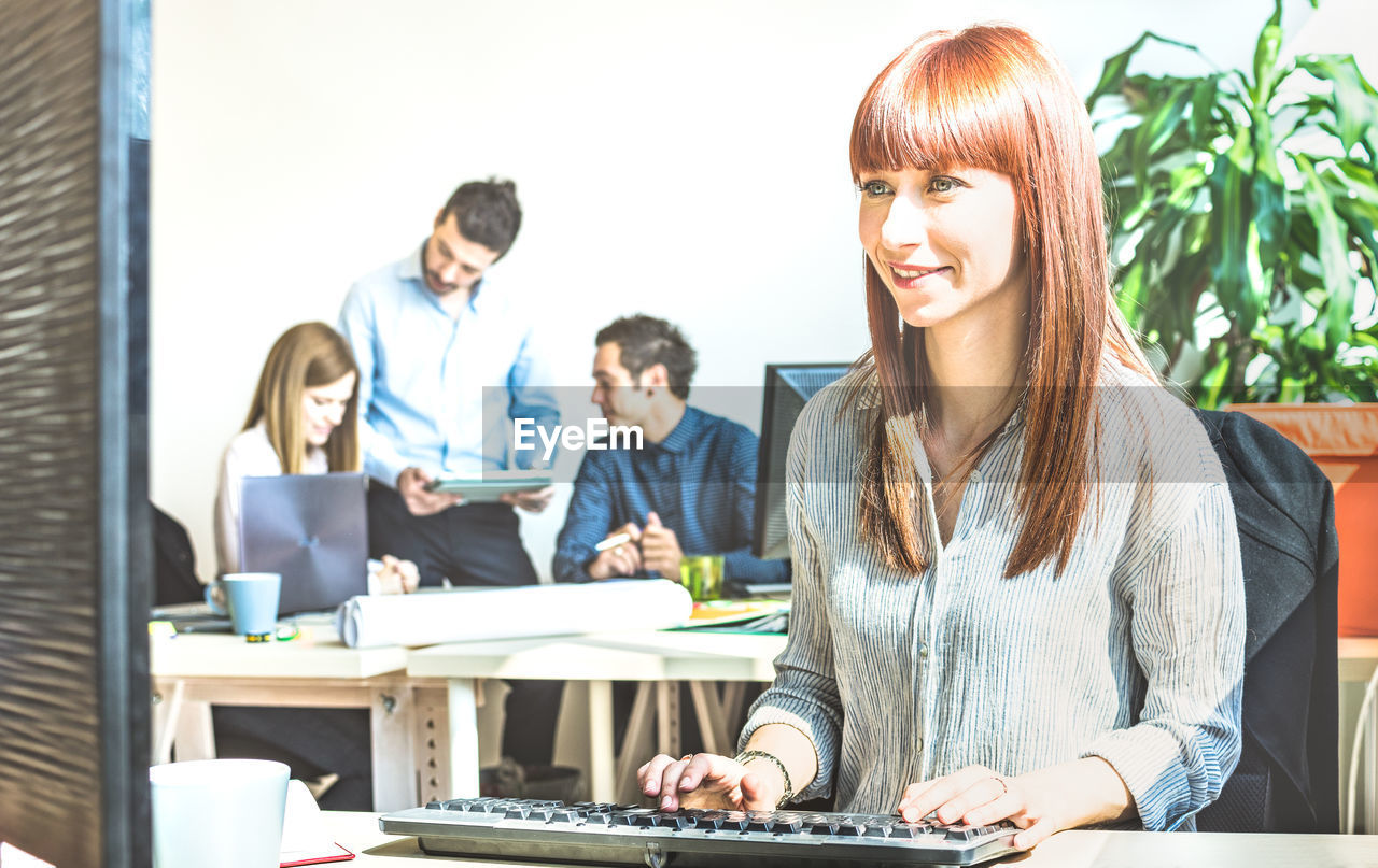 Businesswoman using computer with coworkers in office