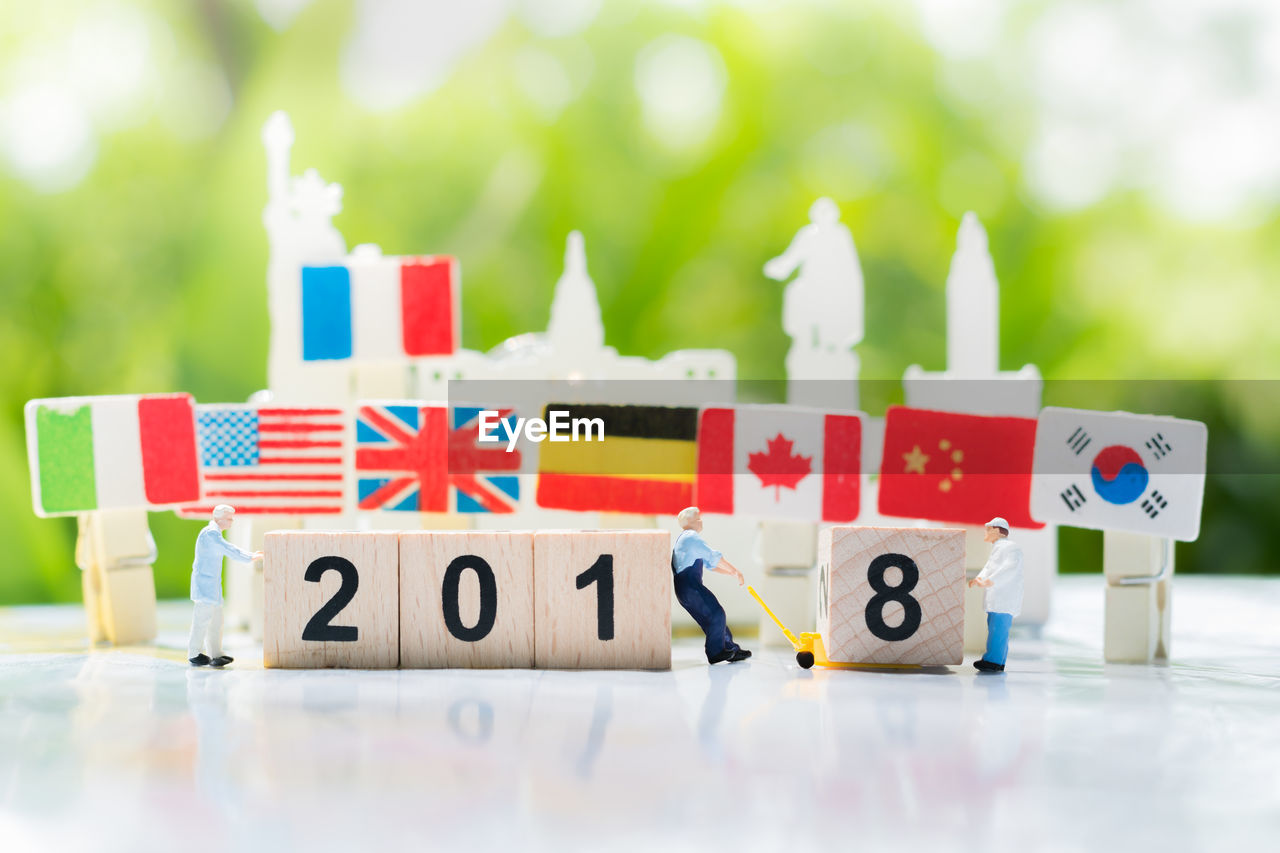 Close-up of wooden blocks with figurines and flags on table at yard