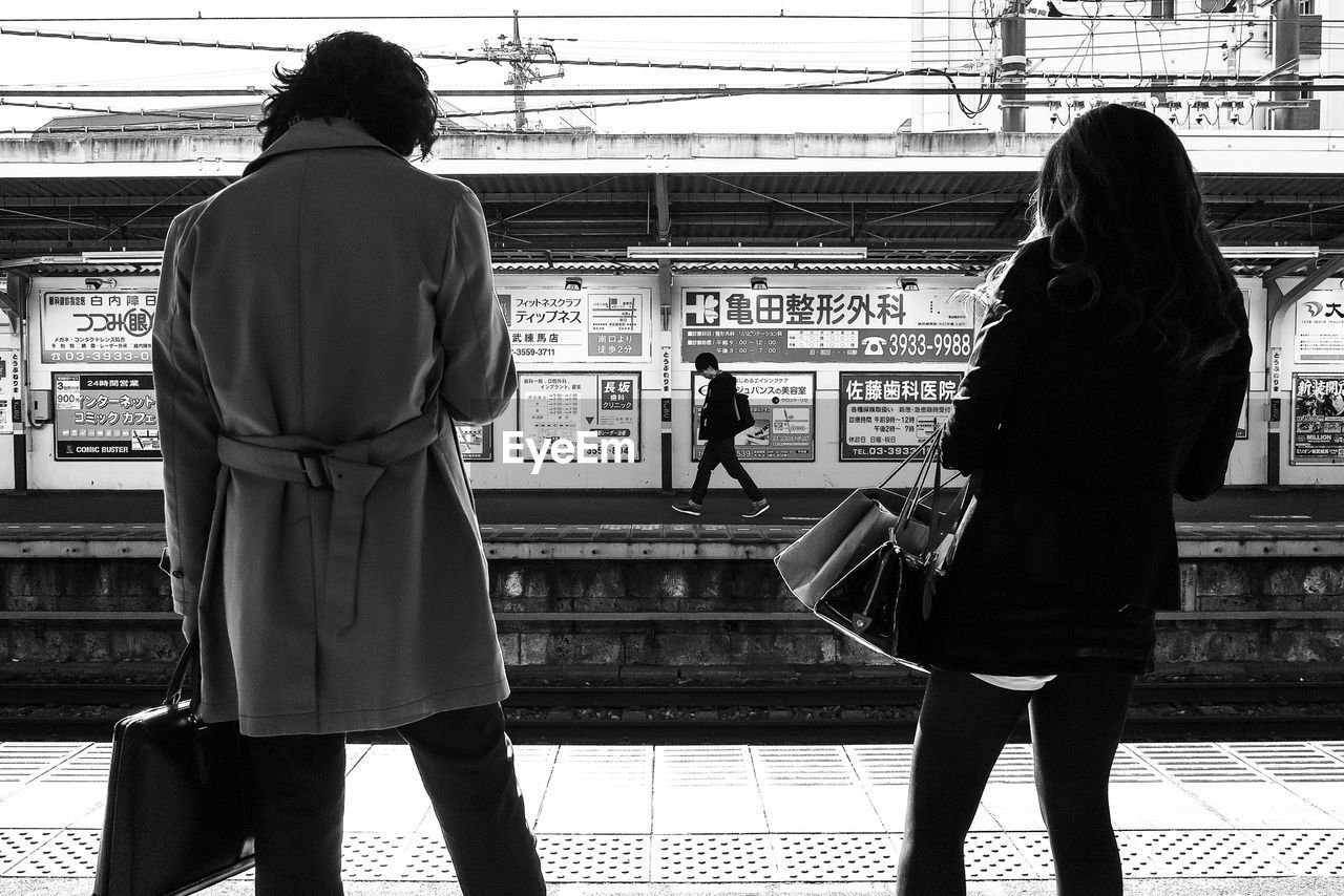 REAR VIEW OF PEOPLE AT RAILROAD STATION