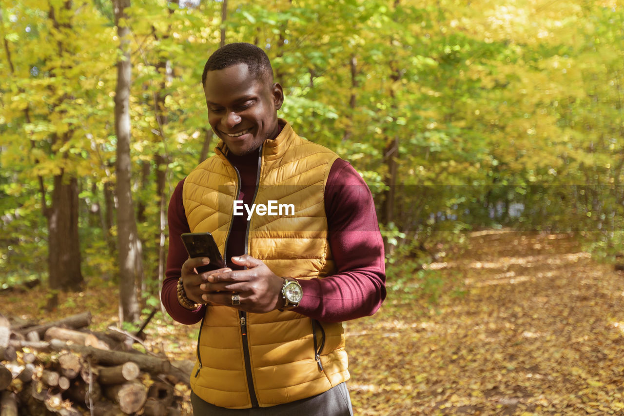 portrait of young man standing in forest during autumn