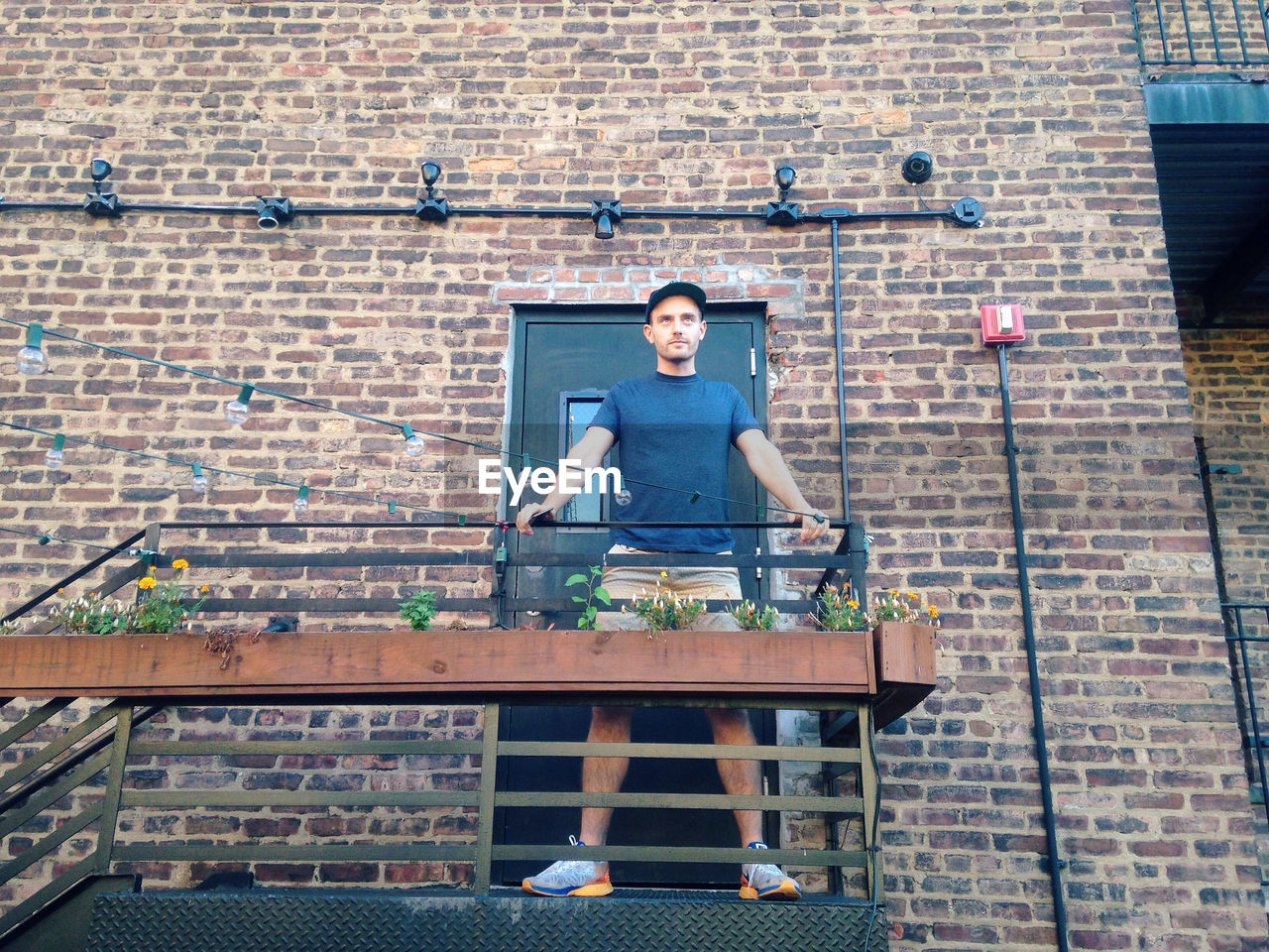 Low angle view of young man standing on fire escape