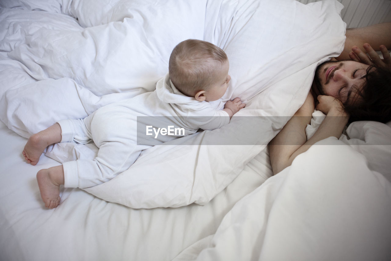 Father with baby son in bed, london, united kingdom