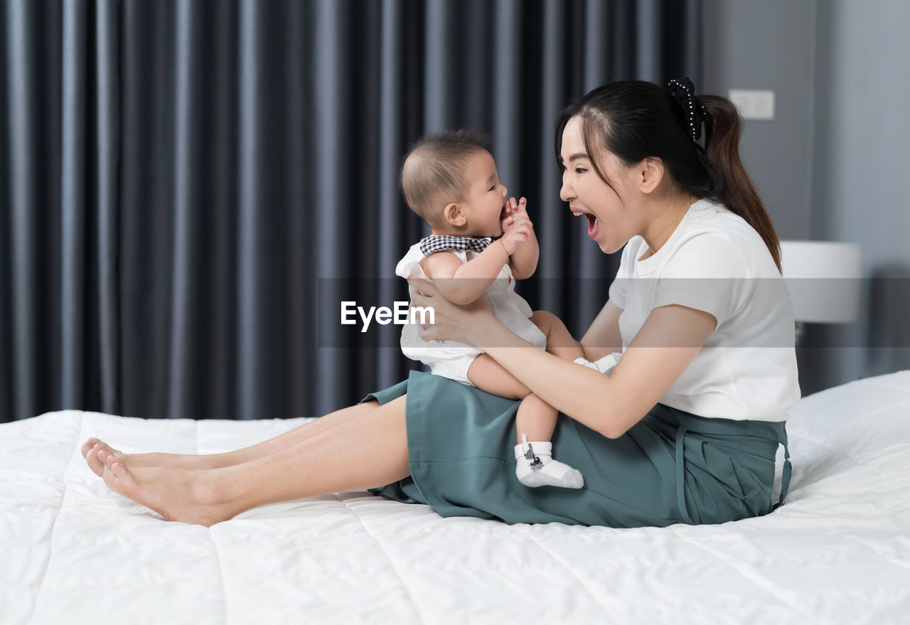 SIDE VIEW OF TWO WOMEN SITTING IN BED