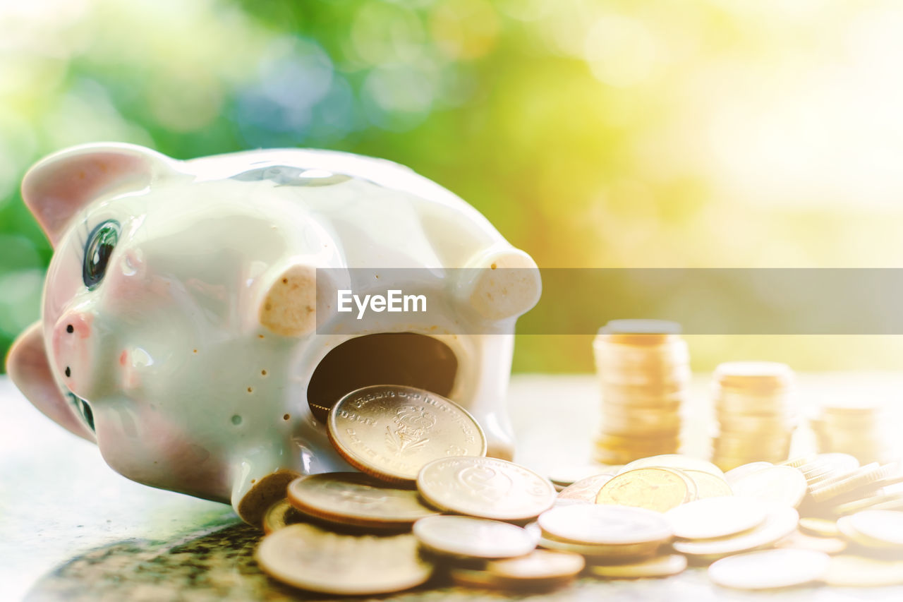 Close-up of coins and piggy bank on table