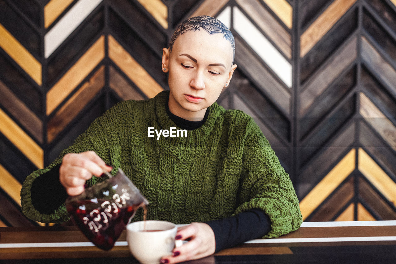 MIDSECTION OF MAN HOLDING COFFEE WHILE SITTING ON TABLE