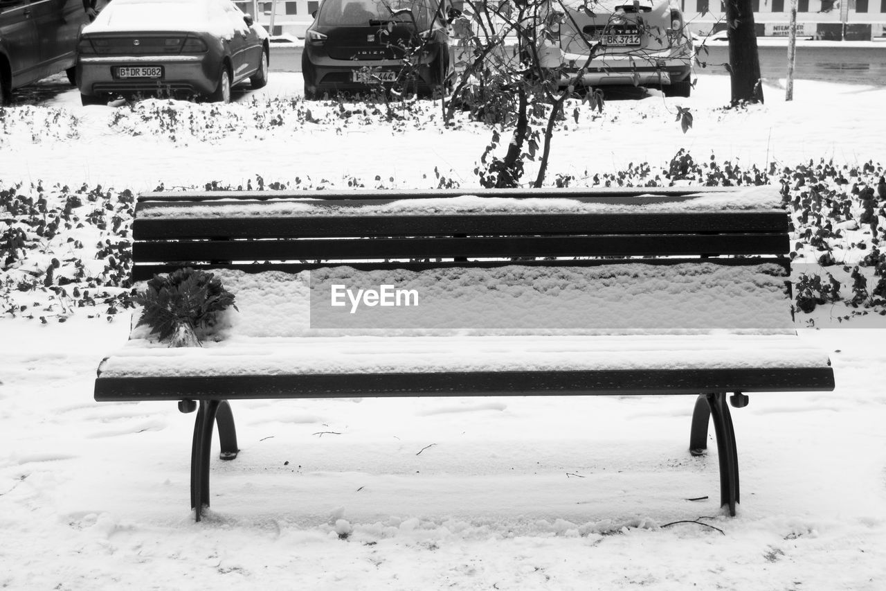 Snow covered empty park bench during winter
