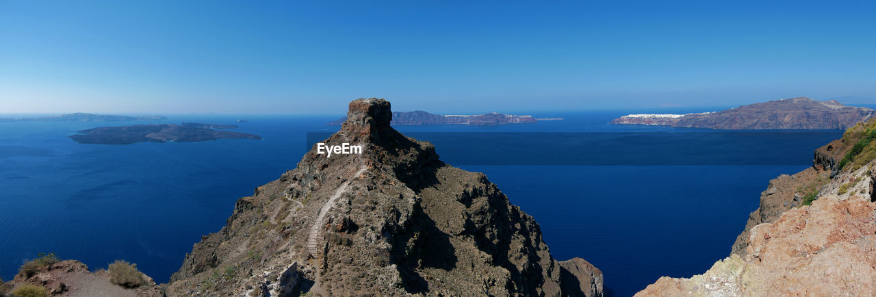 Panoramic view of sea and mountains against blue sky