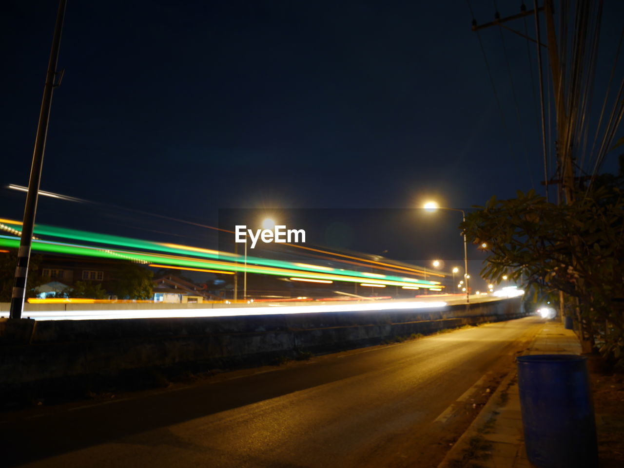 LIGHT TRAILS ON ROAD IN CITY AGAINST SKY AT NIGHT