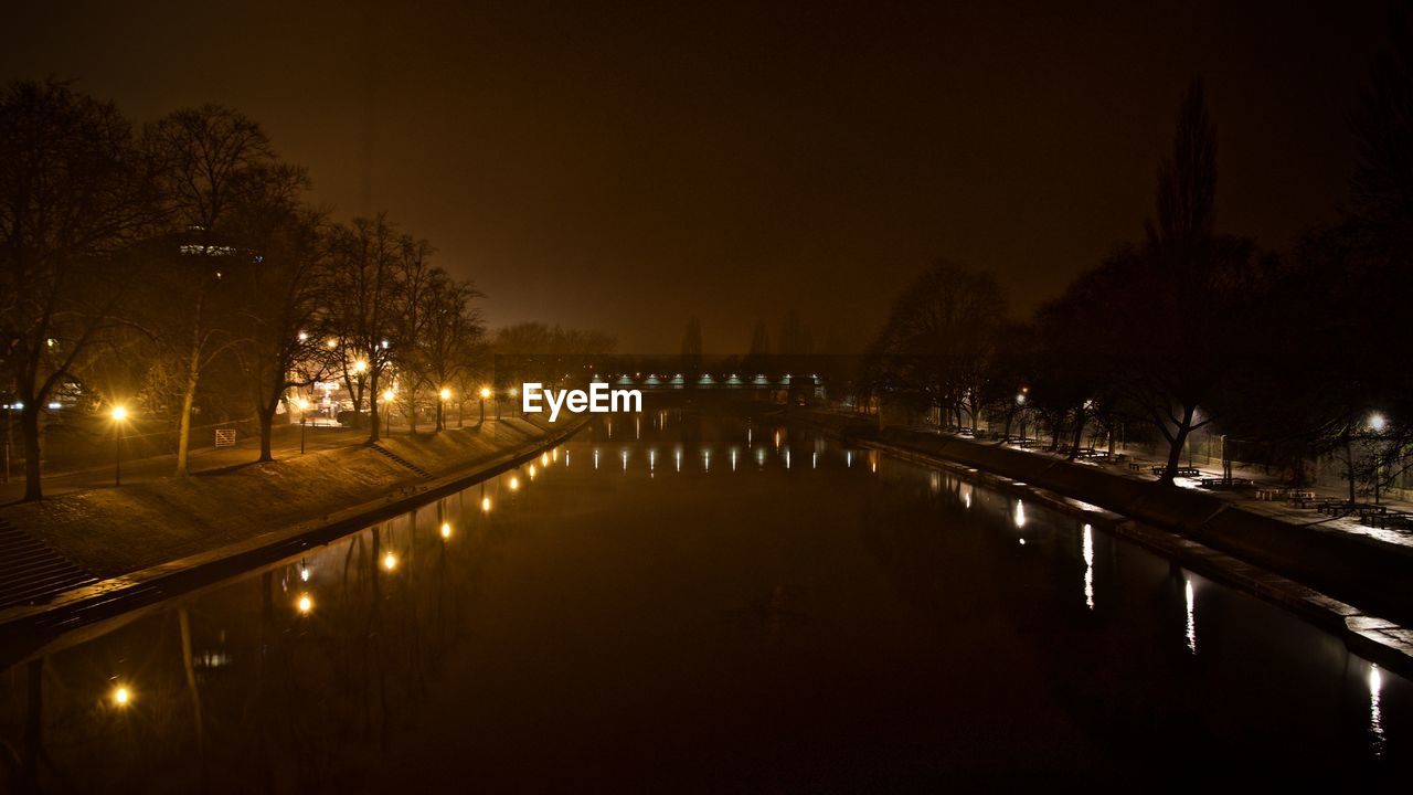 ILLUMINATED BRIDGE OVER RIVER AGAINST SKY