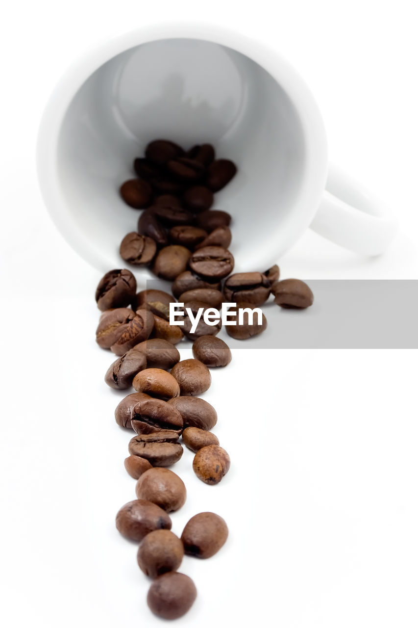 Coffe beans on white mug isolated on white.