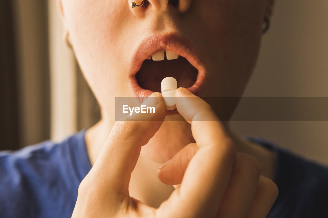 Woman with mouth open taking pill