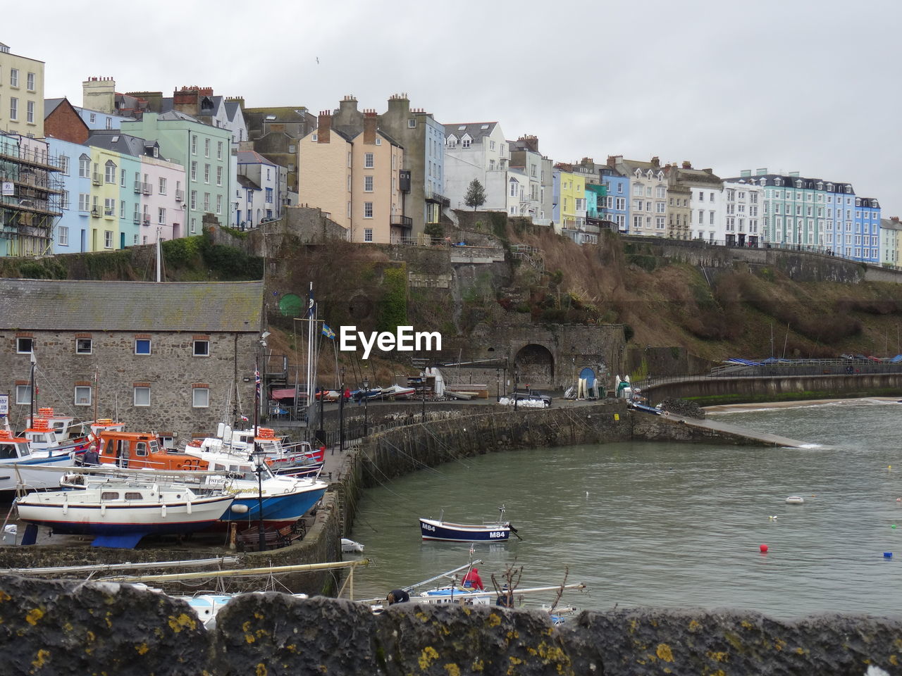 BOATS MOORED IN SEA BY BUILDINGS AGAINST SKY