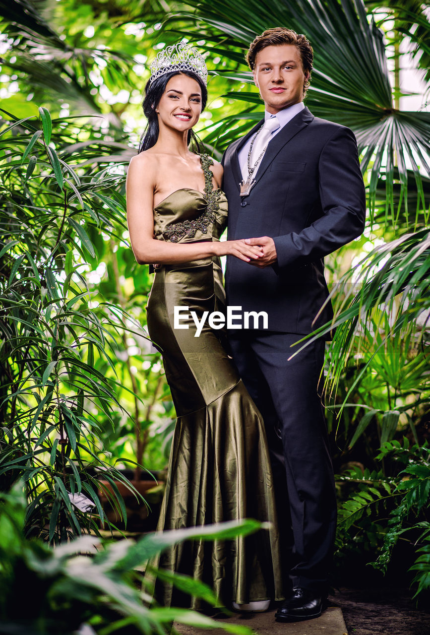 Portrait of smiling young couple standing against trees