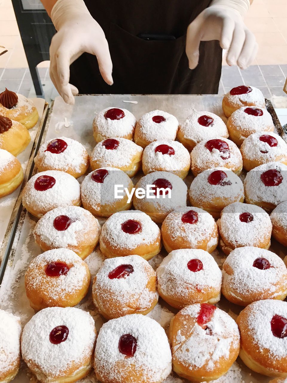 Cropped image of hand with jelly doughnuts on table