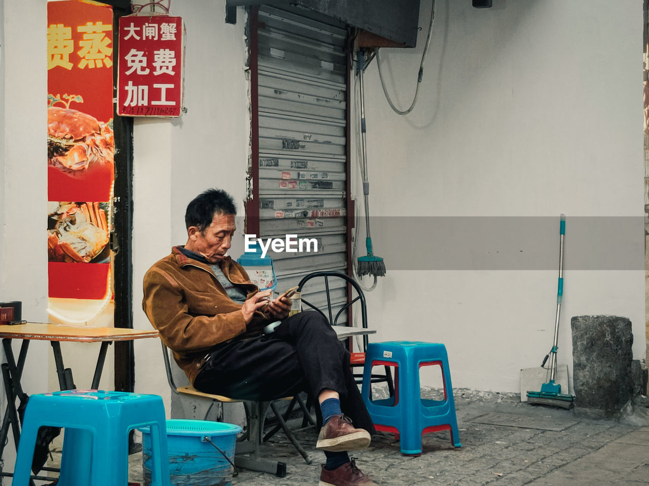 YOUNG MAN USING MOBILE PHONE WHILE SITTING ON SEAT AT BUS