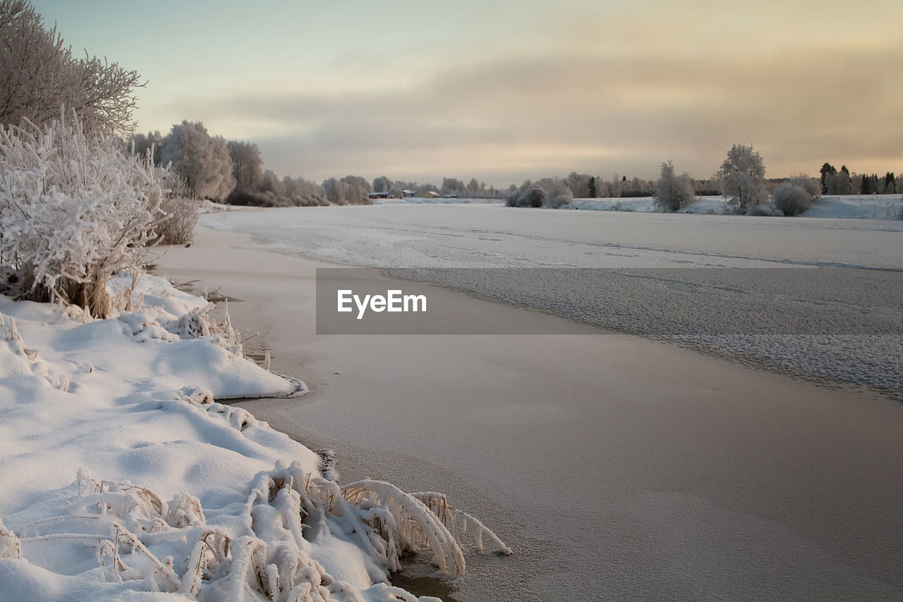 The river water is slowly freezing on a cold winter day at the rural finland. 