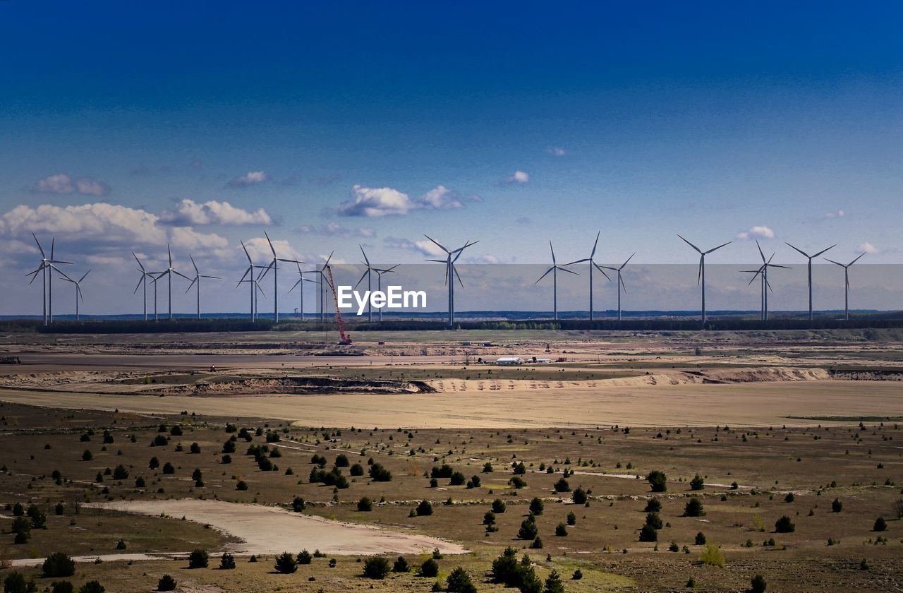 Windmills on field against sky