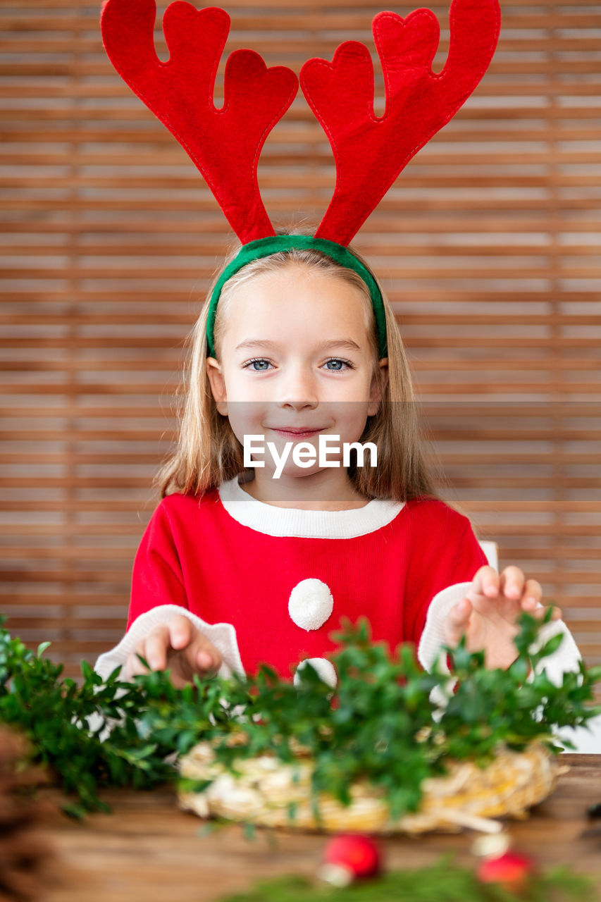 Portrait of cute girl wearing antler at home