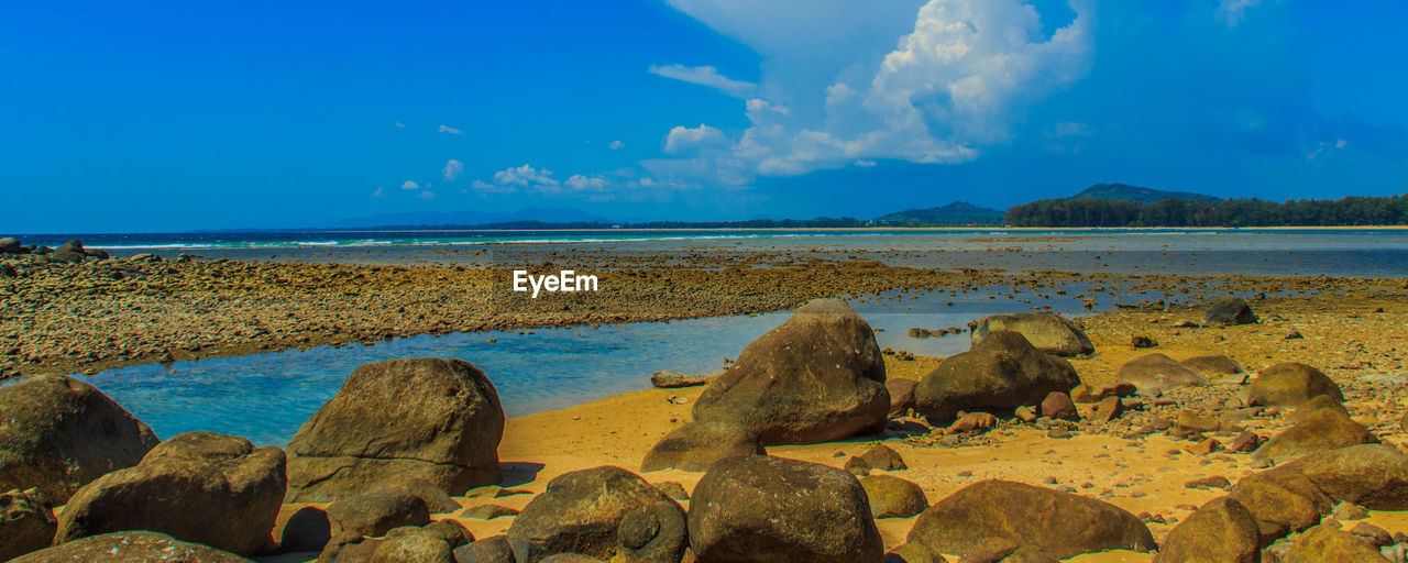 Close-up of rocks by sea against blue sky