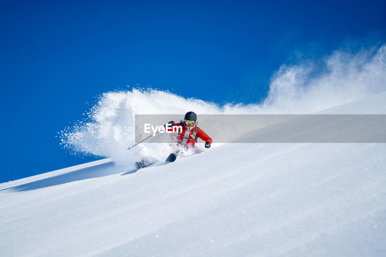 Woman skiing on snowcapped mountain against sky