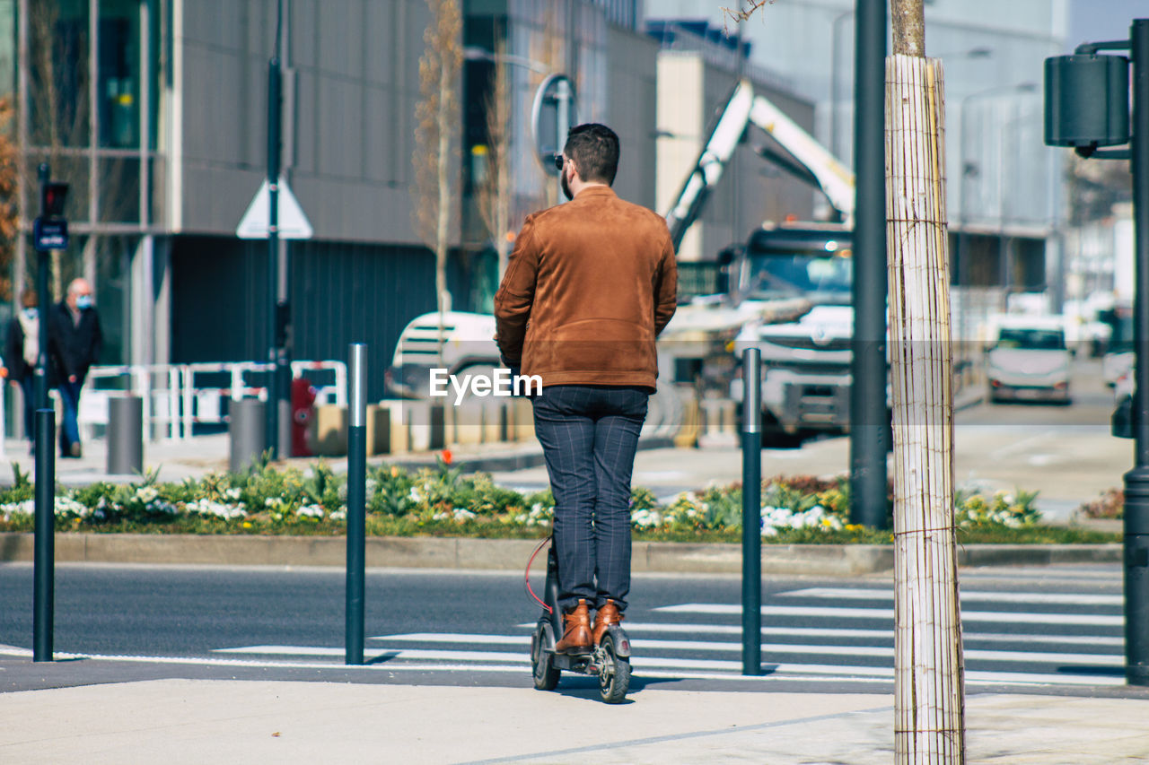 FULL LENGTH REAR VIEW OF MAN WALKING ON SIDEWALK