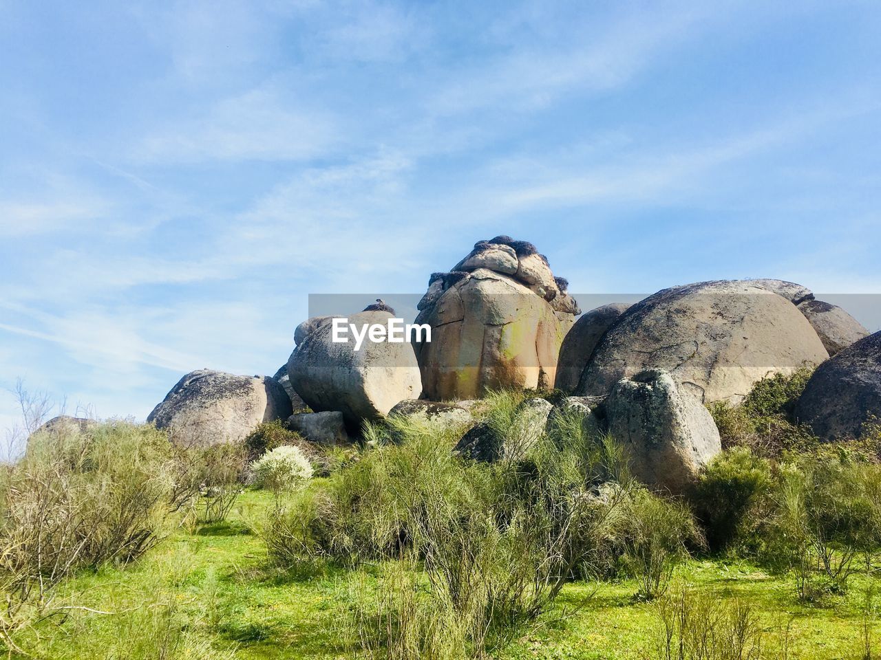 LOW ANGLE VIEW OF SCULPTURE ON ROCK FORMATION ON FIELD AGAINST SKY