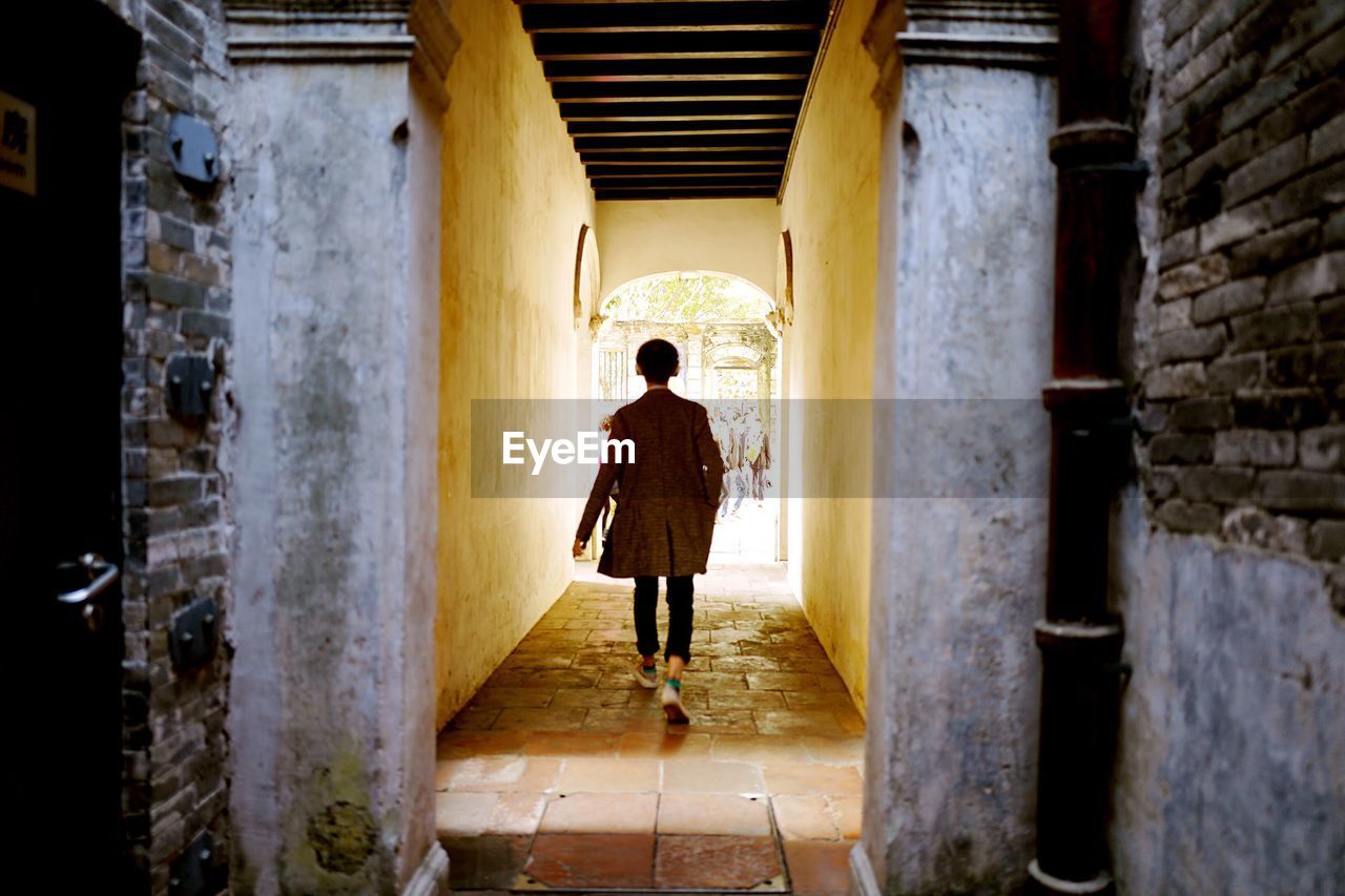 Full length rear view of man walking on narrow walkway