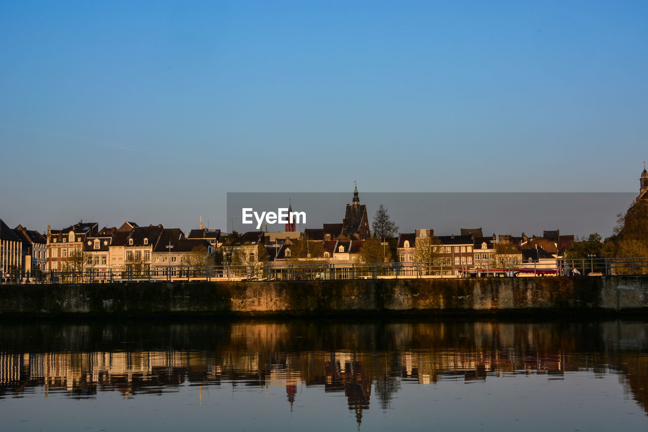 Buildings reflection in lake against blue sky