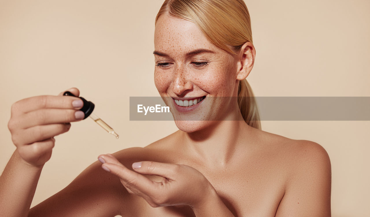 close-up of young woman applying make-up against white background