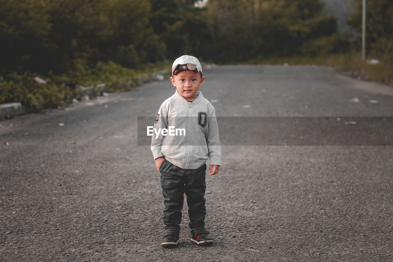 Portrait of toddler boy standing on road