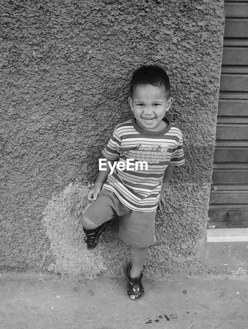 Portrait of cheerful boy standing by wall