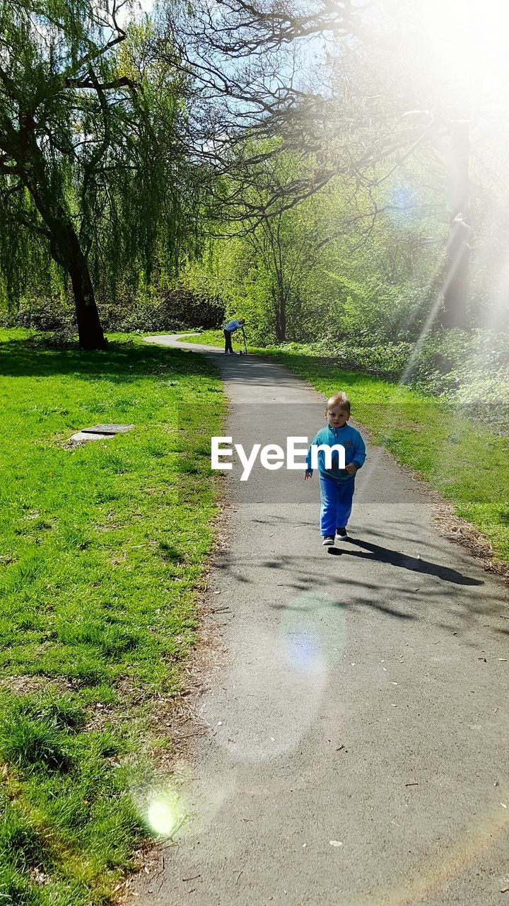 Full length of boy walking on footpath on sunny day