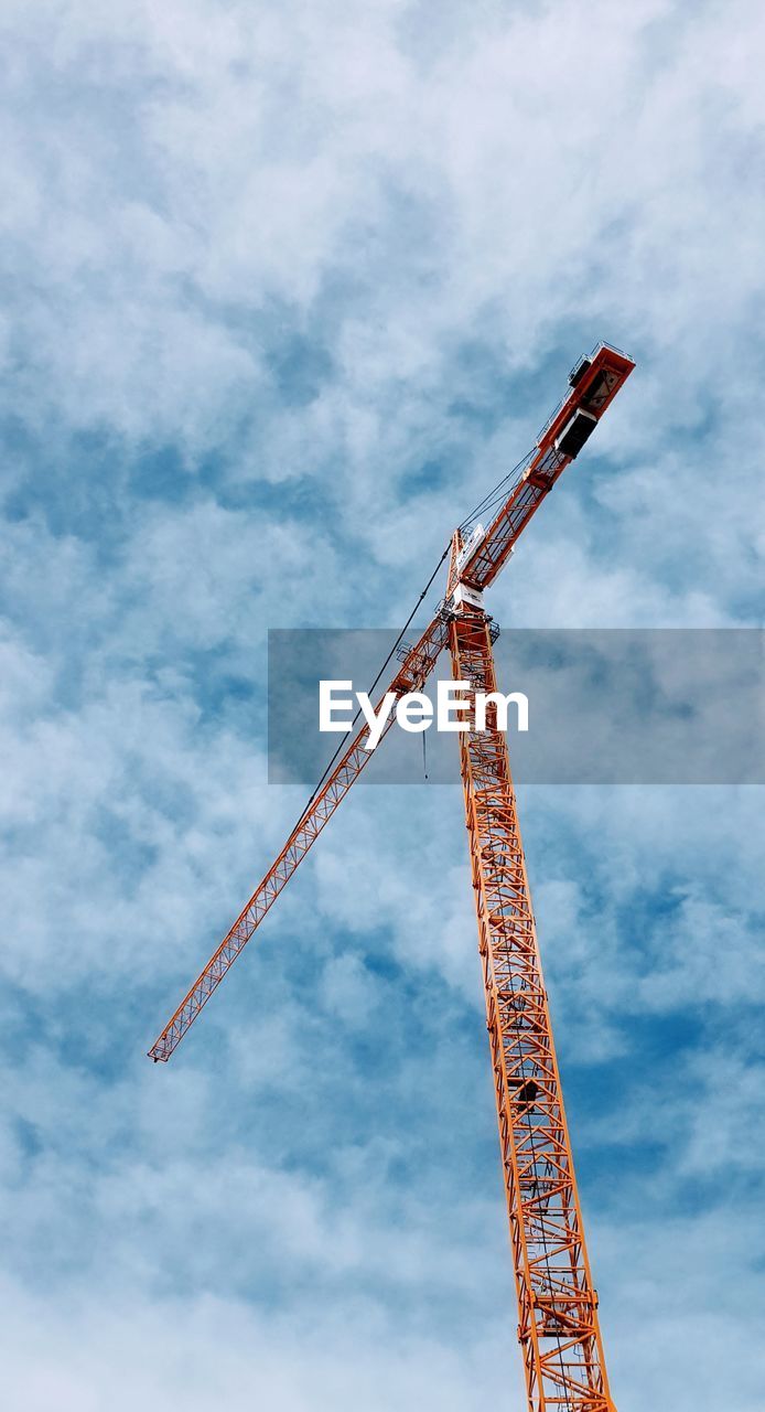 Low angle view of crane against cloudy sky