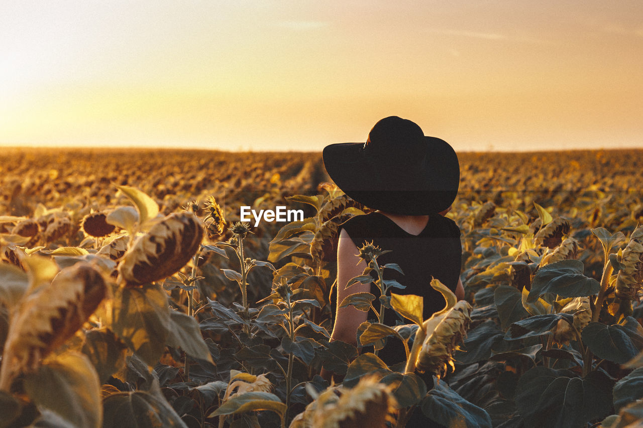 Woman in sunflower field during sunset