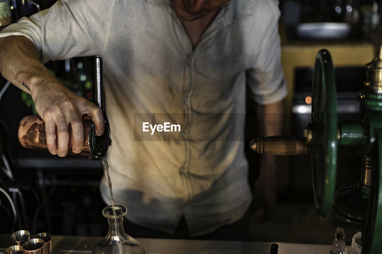 MIDSECTION OF MAN WORKING IN GLASS