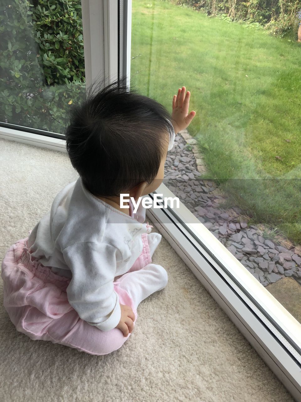 High angle view of baby girl looking through window at home