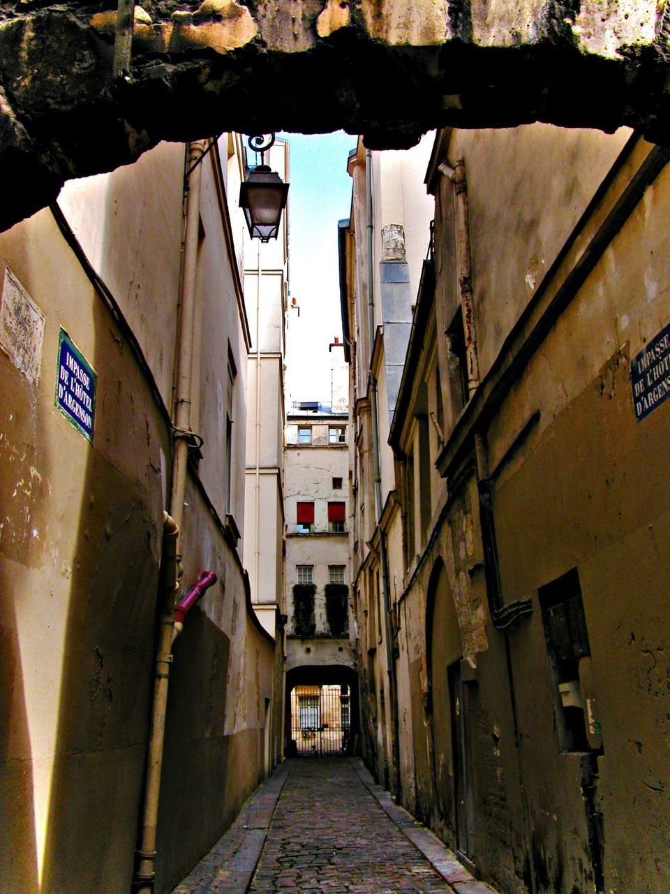 NARROW ALLEY WITH BUILDINGS IN BACKGROUND