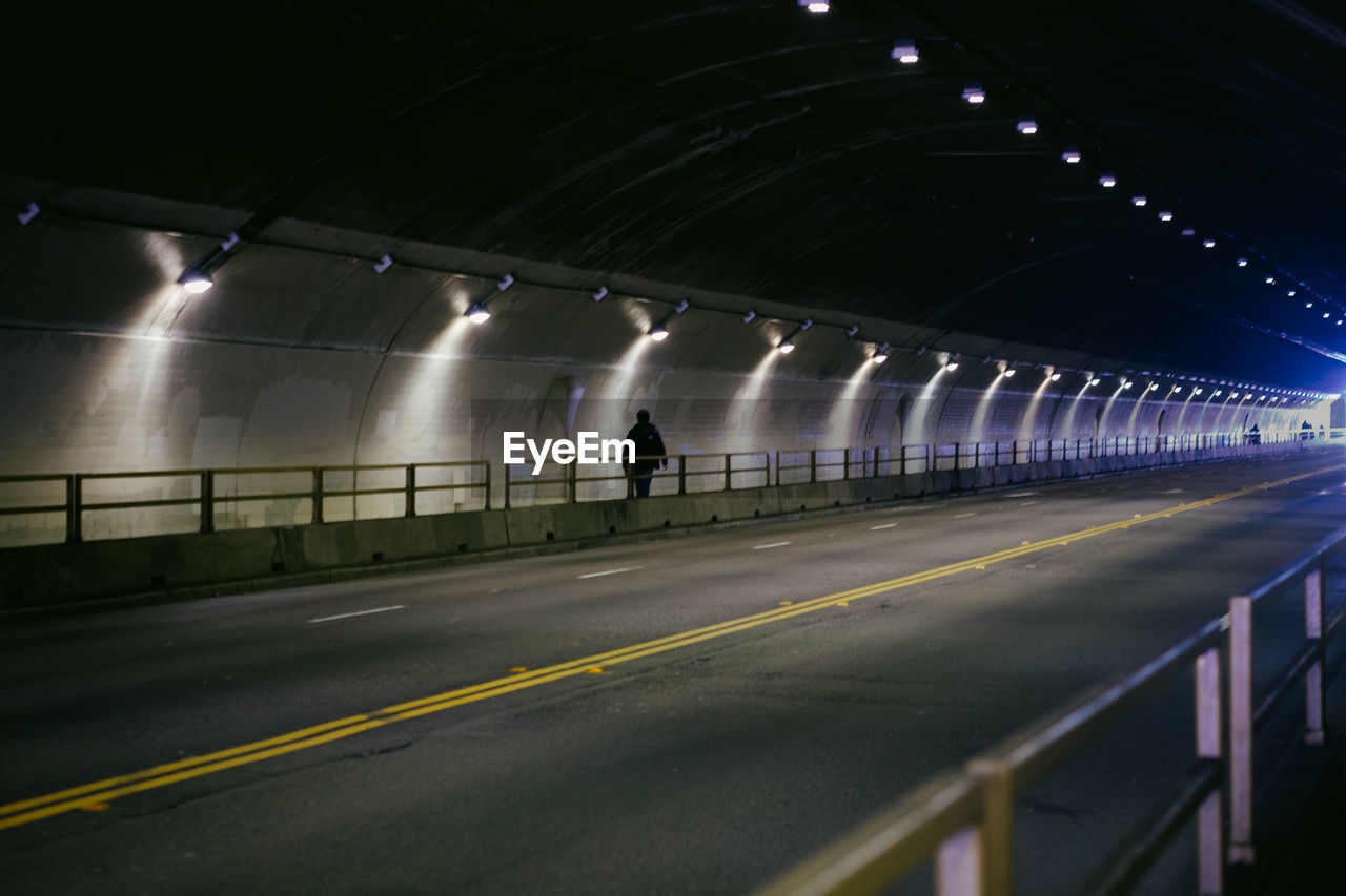 Man on illuminated road in stockton tunnel