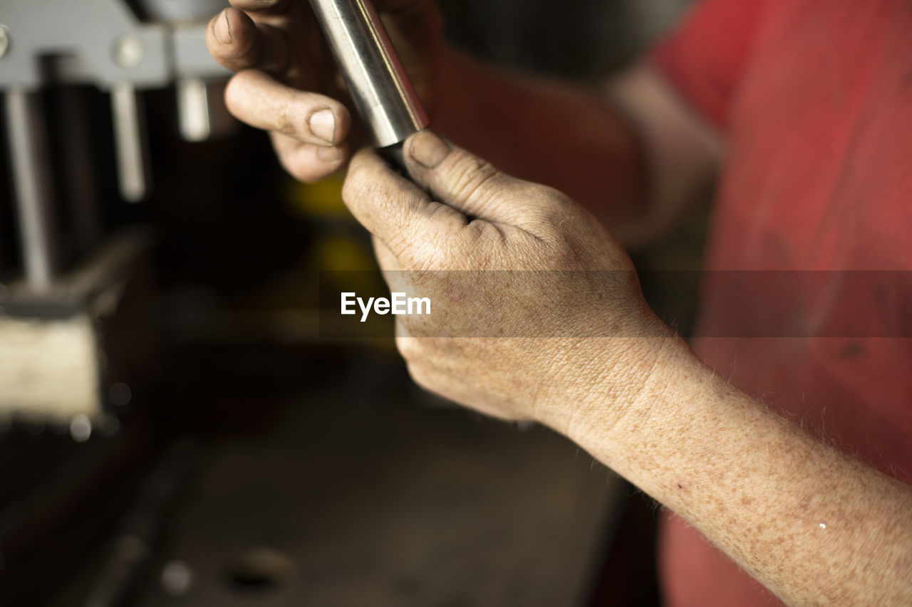 CLOSE-UP OF MAN WORKING AT WORKSHOP