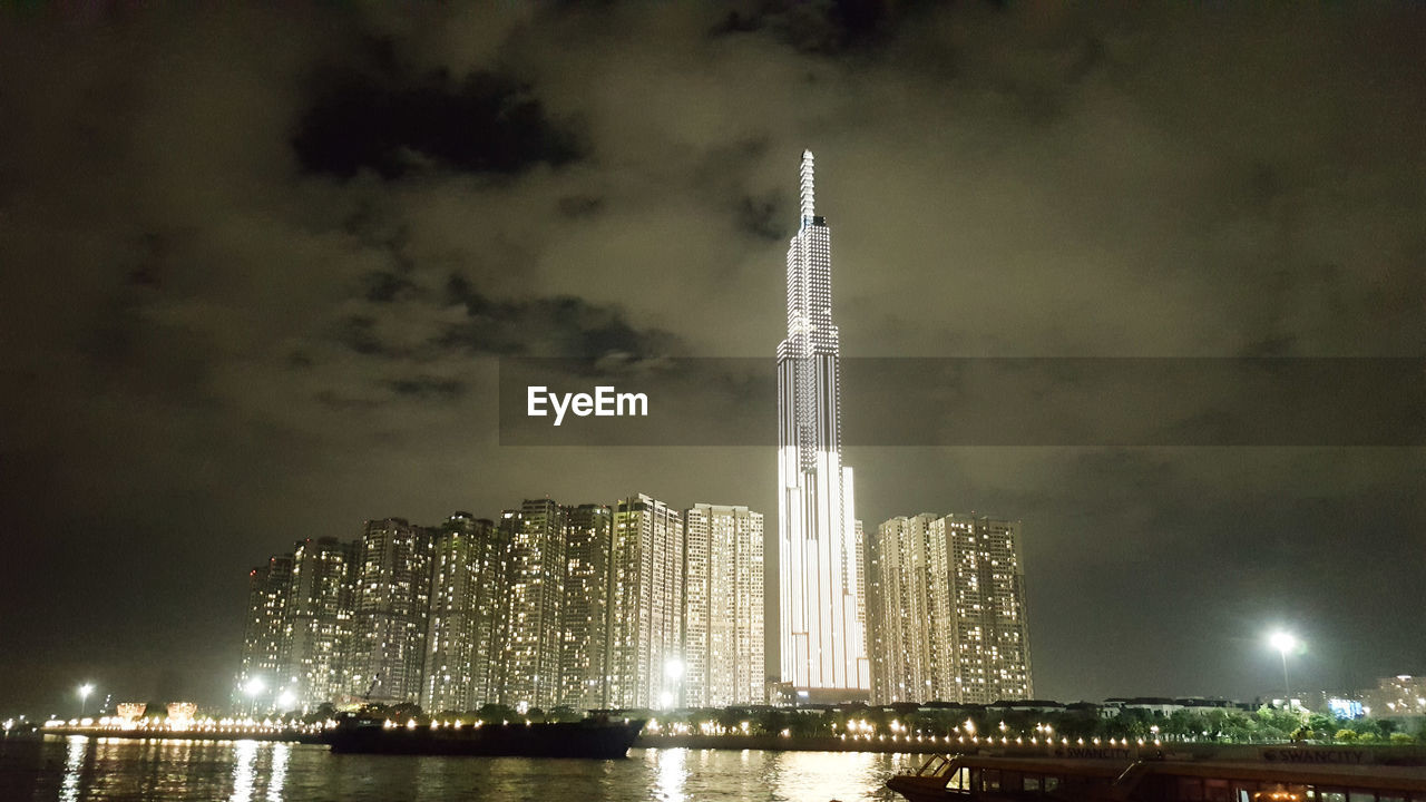 ILLUMINATED MODERN BUILDINGS AGAINST SKY AT NIGHT