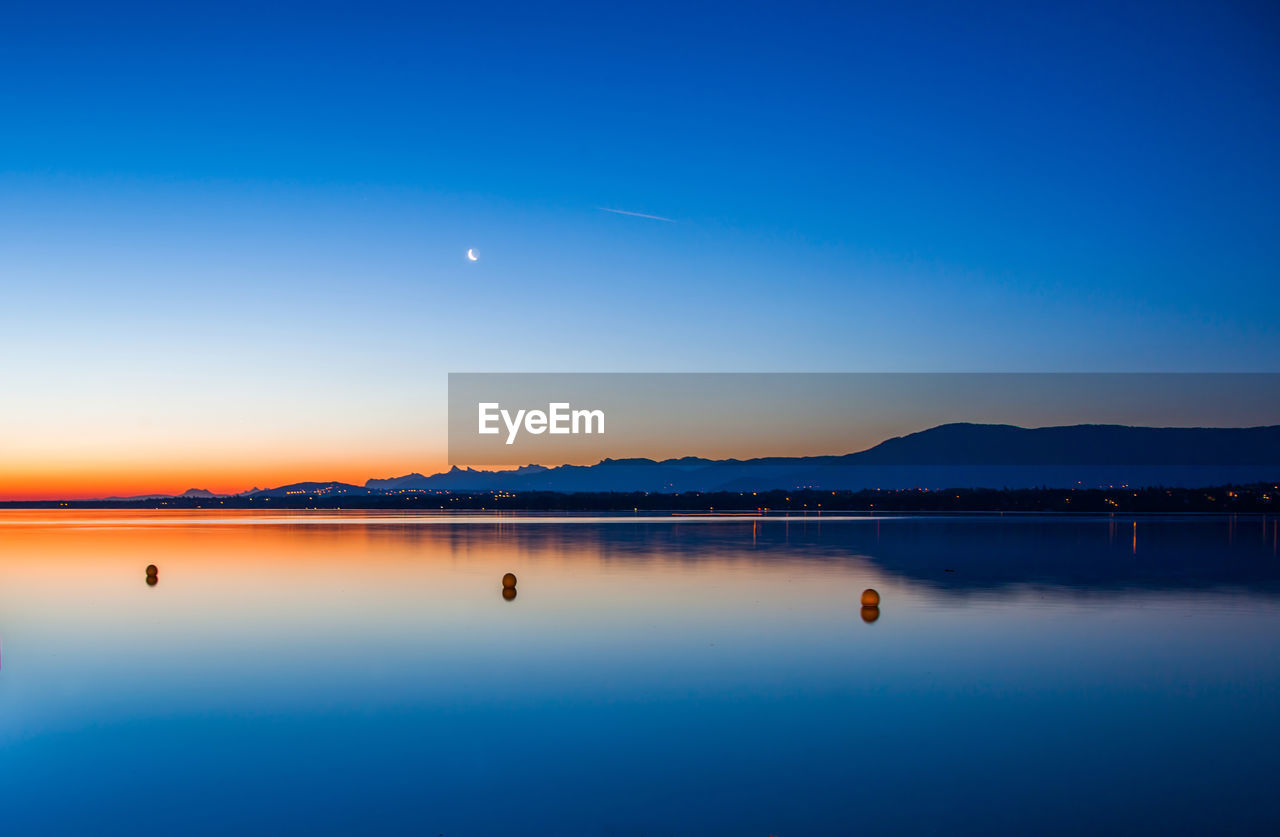 Scenic view of calm lake against sky during sunset