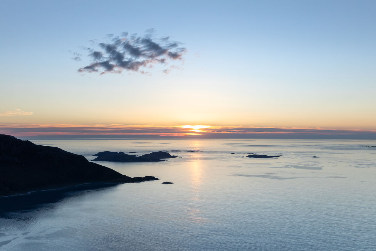 Scenic view of norwegian sea against sky during sunset with single grey cloud seen from mountain top