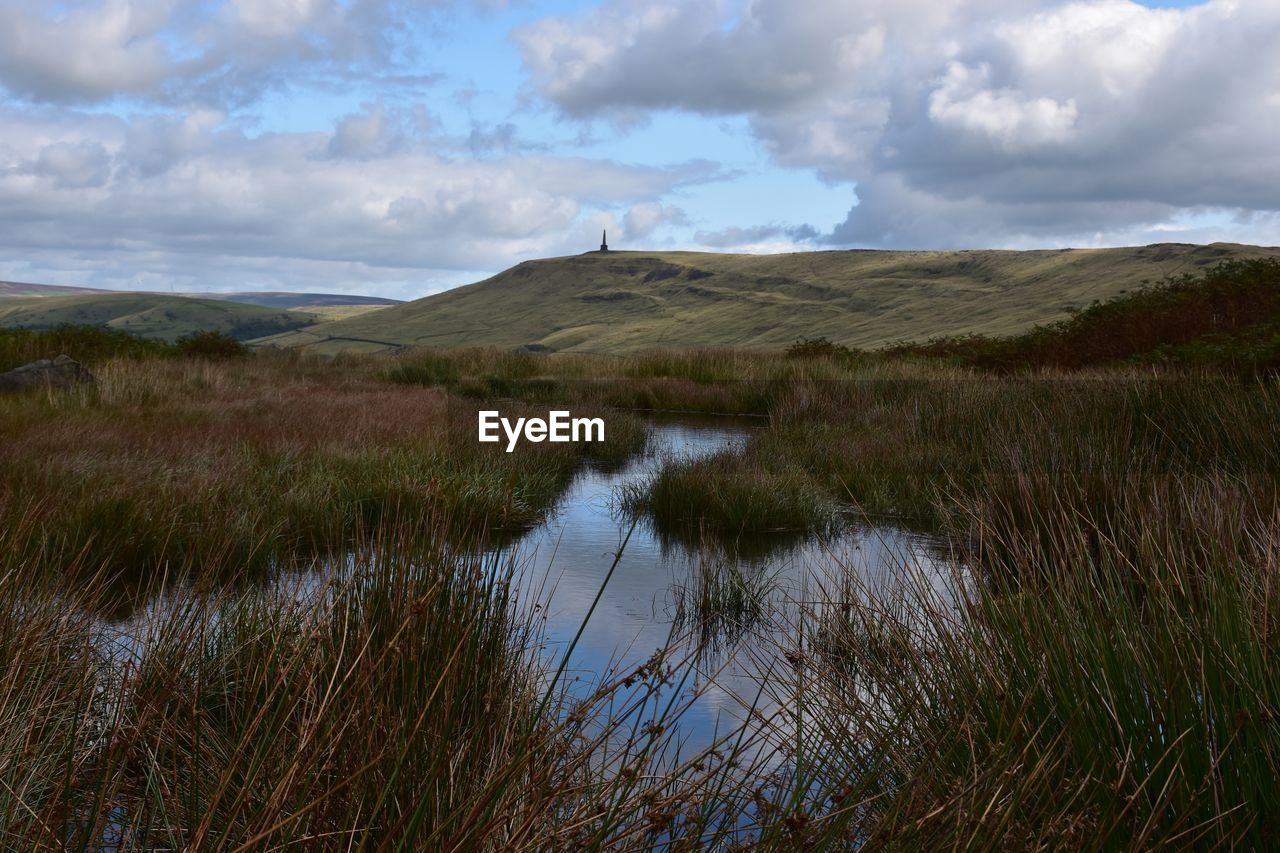 Scenic view of moorland with stoodley pike in the distance and pond in the foreground