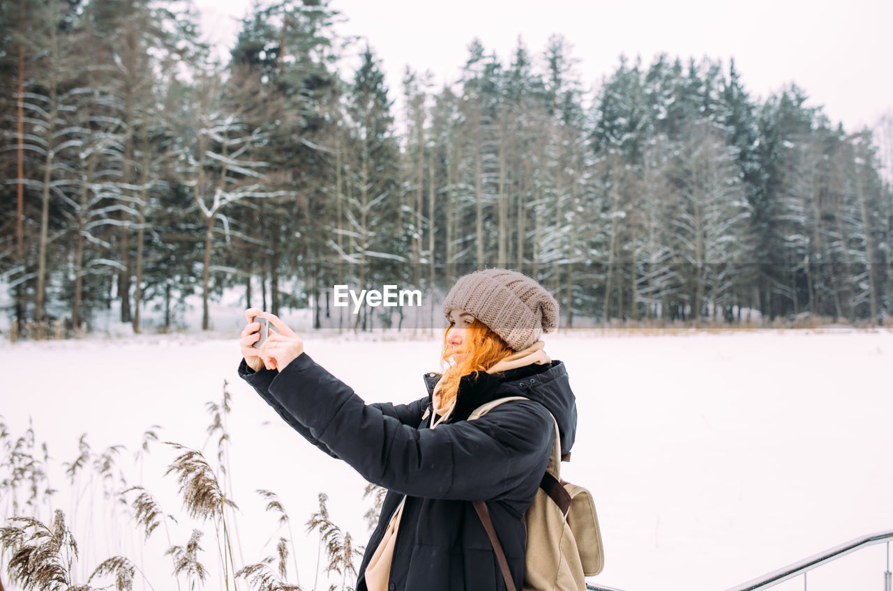 rear view of woman standing on snow covered landscape