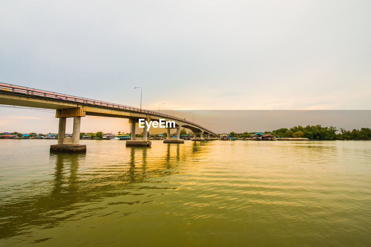 BRIDGE OVER CALM RIVER AGAINST SKY