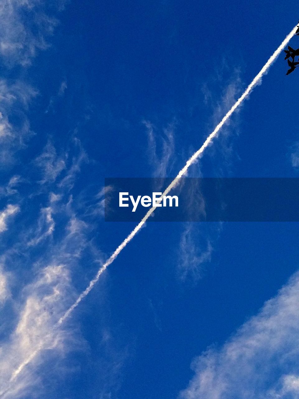 LOW ANGLE VIEW OF VAPOR TRAILS IN BLUE SKY