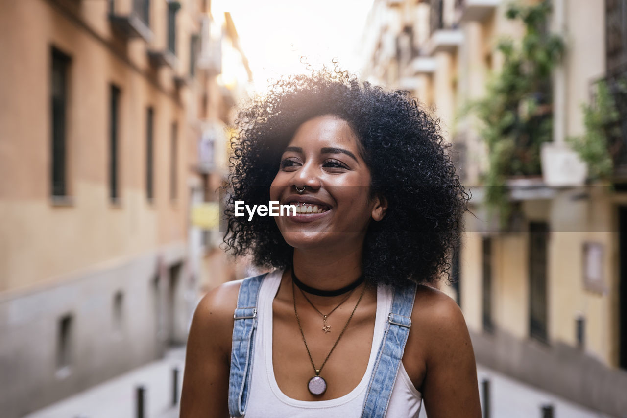 Smiling young woman standing against buildings