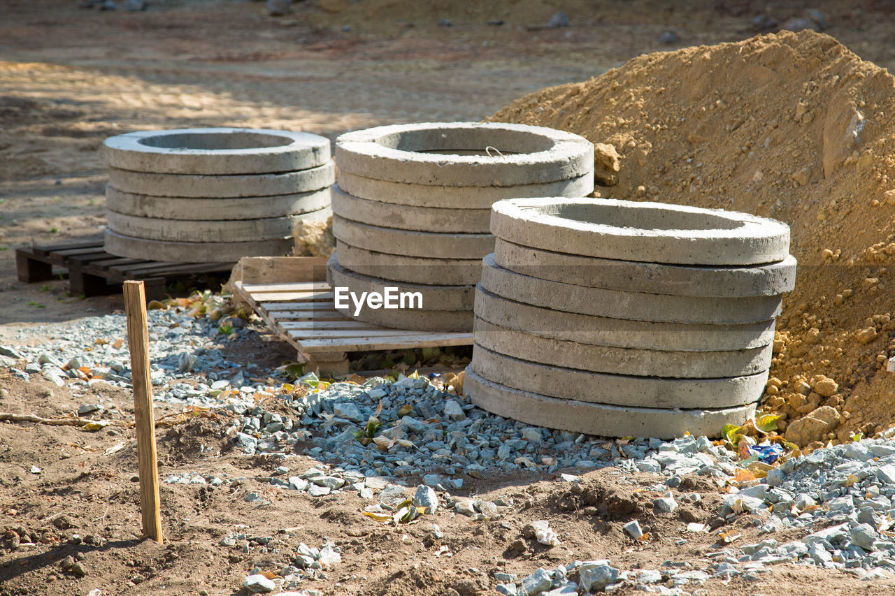Reinforced concrete rings lie on pallets at the construction site.