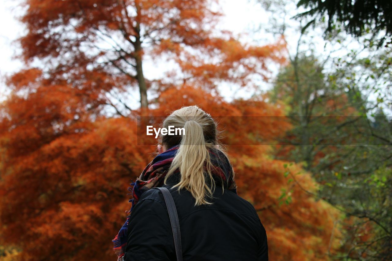 Rear view of woman standing against autumn trees
