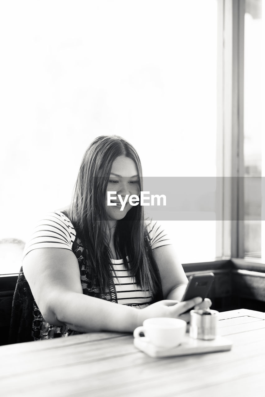 Portrait of woman using phone at coffee shop